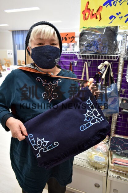 前垂れを改造し、アイヌ文様を縫い付けたバッグを手に越野さん