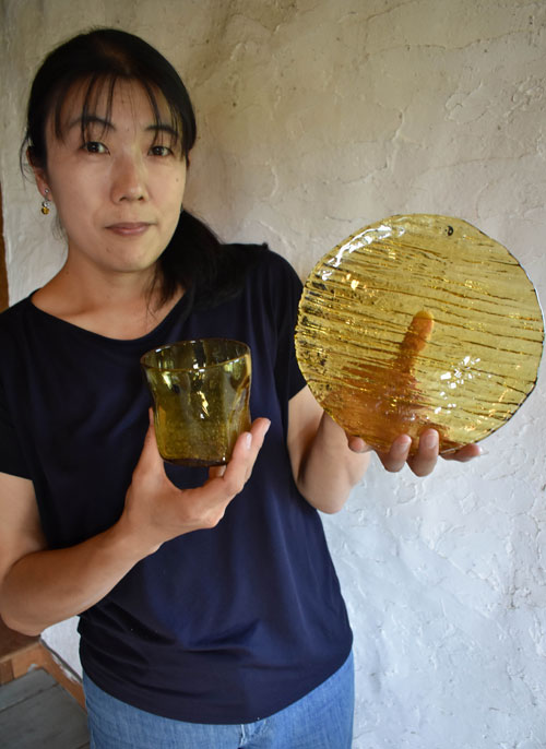 川湯温泉の天然成分が入ったガラス工芸品「川湯温泉ユノハナガラス」を手にする木名瀬さん